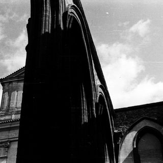 Gothic architecture with arched windows and cloudy sky.