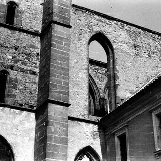 Ruined Gothic-style church exterior with arched windows.
