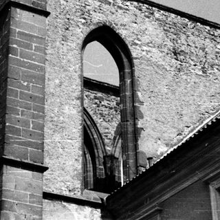 Ruined Gothic-style church exterior with arched windows.