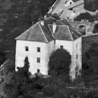 Historic castle town nestled in hilly, forested landscape.