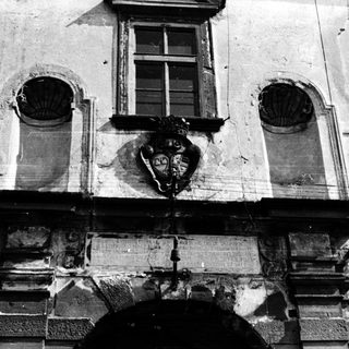 Baroque-style building facade with weathered reliefs and coat of arms.