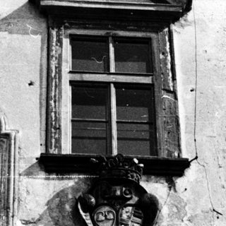 Baroque-style building facade with weathered reliefs and coat of arms.
