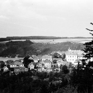 Rural village nestled by lake and forest.