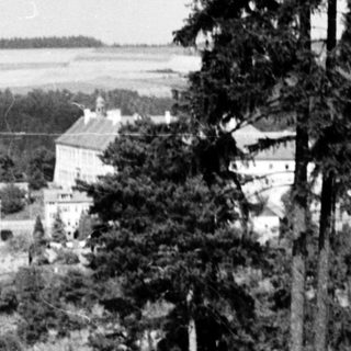 Rural landscape with forest, house, and distant fields.
