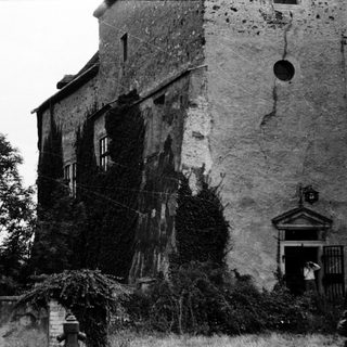Abandoned stone building with ivy-covered walls.