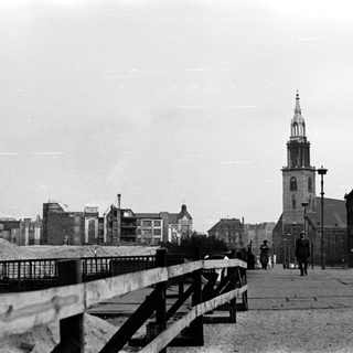 Black-and-white city street with historic church tower.