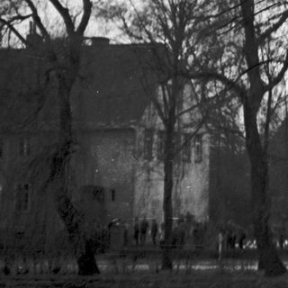 Barren trees, old stone building, quiet park scene.