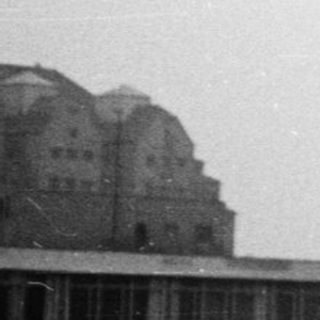 Urban scene with mid-century high-rise building under construction.