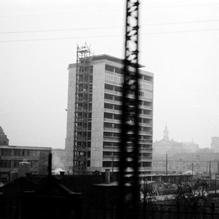 Urban scene with mid-century high-rise building under construction.