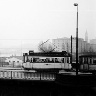 Vintage tram crossing bridge in foggy city.