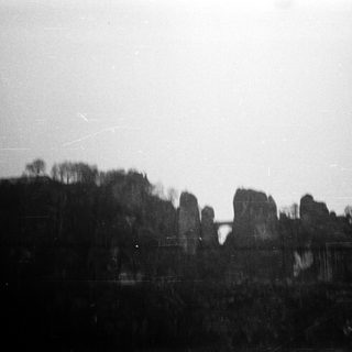 Blurred ruins of stone structures in wooded area.