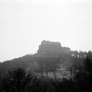 Towering sandstone rock formation in forested landscape.