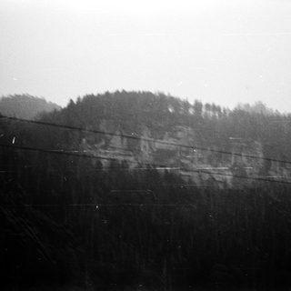 Rural landscape with forested hillside and power lines.