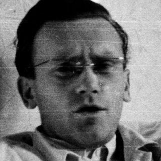 Young man in hospital gown, seated indoors.