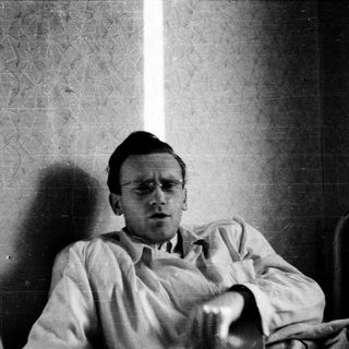 Young man in hospital gown, seated indoors.