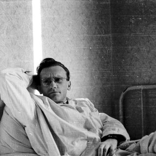 Man resting or lying in hospital gown.
