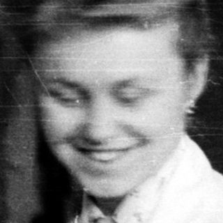 Young woman in nurse's uniform smiling indoors.