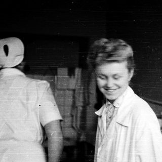 Young woman in nurse's uniform smiling indoors.