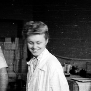 Young woman in nurse's uniform smiling indoors.