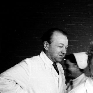 Two people in lab coats posing together indoors.