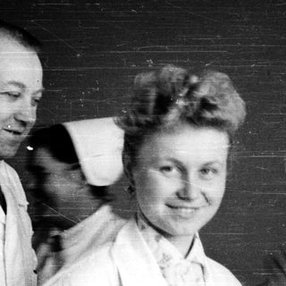 Two people in lab coats posing together indoors.