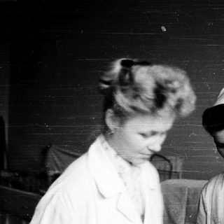 Nurses in early 20th-century uniforms indoors.