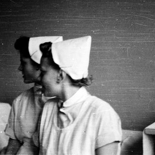 Nurses in traditional white uniforms and caps.