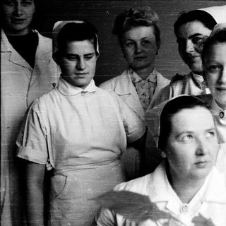 Nurses in traditional 1940s-50s uniforms posing together.