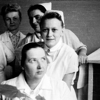 Nurses in traditional 1940s-50s uniforms posing together.