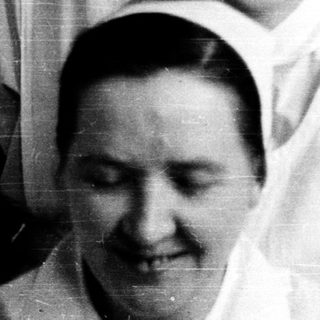 Nurses in traditional uniforms posing together indoors.