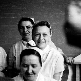 Nurses in traditional uniforms posing together indoors.