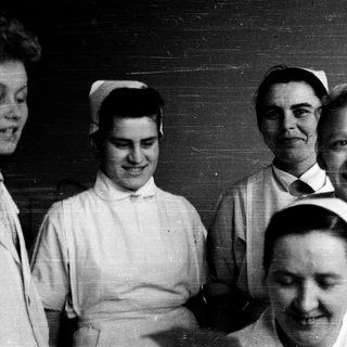 Nurses in traditional uniforms posing together indoors.