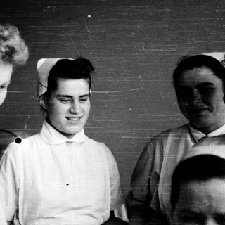 Nurses in traditional white uniforms, mid-20th century.
