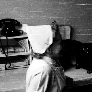 Nurse using vintage telephone in medical office.