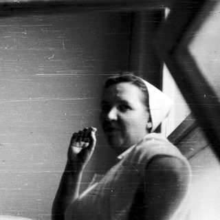 Man holding cigarette near open window.