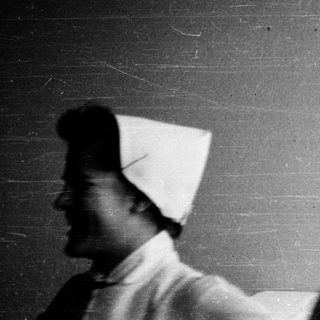 Nurses in vintage uniforms posing indoors.