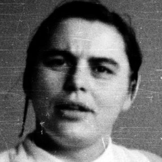 Black-and-white portrait of a person indoors.
