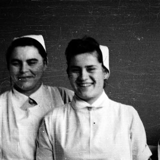Four nurses in vintage uniforms posing together.