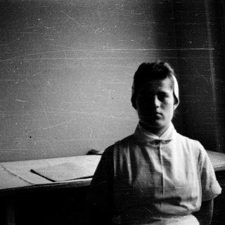Young person indoors, early 20th-century style clothing.
