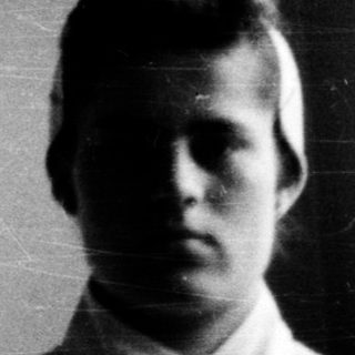 Young person indoors, early 20th-century style clothing.