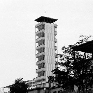Tall concrete observation tower with adjacent buildings.
