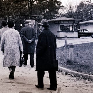People walking on a rural roadside path.
