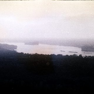 Misty river valley with forested hills.