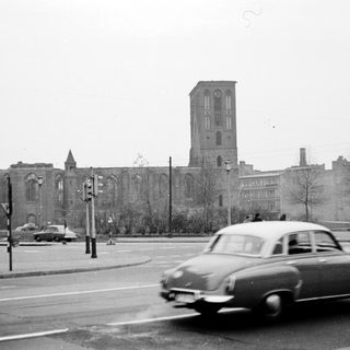 Vintage car passing old stone church building.