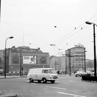 Vintage city street with vintage vehicles and billboards.