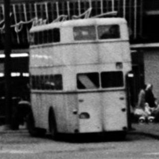 Large multi-story building with vintage cars and bus.