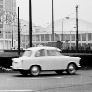 High-rise building with mural, vintage cars, urban street scene.