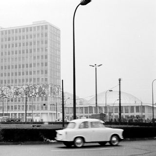 High-rise building with mural, vintage cars, urban street scene.
