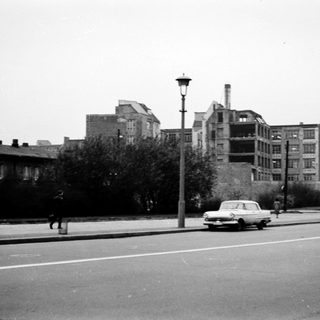 Vintage urban street with old buildings, car, pedestrian.