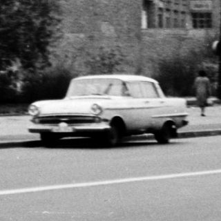 Vintage urban street with old buildings, car, pedestrian.